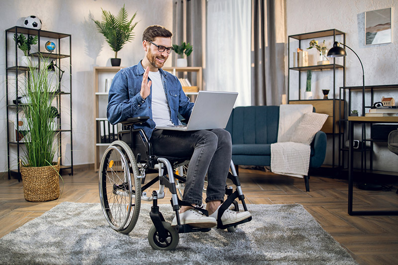 male actor seated in a wheelchair uses a laptop