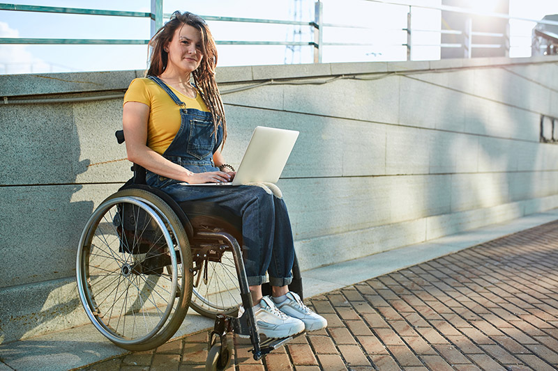 disabled woman in ultralight wheelchair holding a laptop