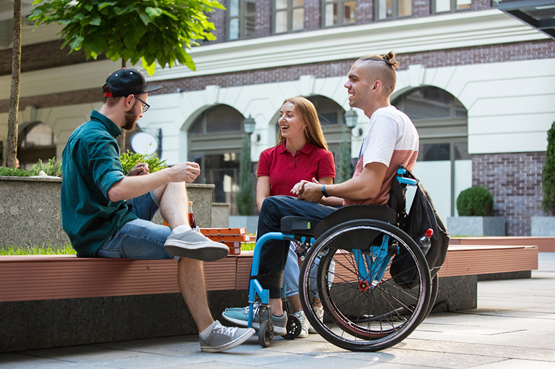 group of friends eating outdoors with one guy in a wheelchair